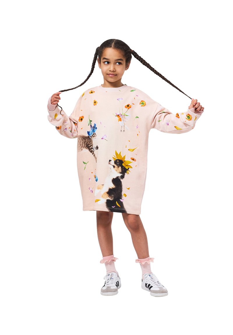 Korall rózsaszín, túlnyúló pulcsiruha virágmintákkal és állatillusztrációkkal. Bordás mandzsetták és szegély, pasztell bokazoknival és sportcipővel viselve.