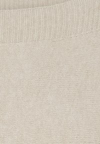 Beige strikket stof med en ribbet halsudskæring, der har en glat tekstur og en jævn, ensartet vævning gennem hele stoffet.