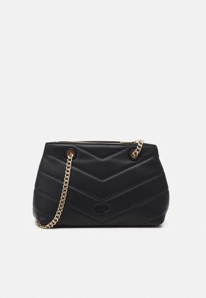 Sac à main noir matelassé avec bandoulière chaîne dorée et fermeture éclair, présentant un motif chevron et un logo embossé discret sur le devant.