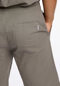 Grå shorts i texturerat tyg har en bakfick med dragkedja och resårmidja för ökad komfort. Minimal varumärkesskylt på fickan.
