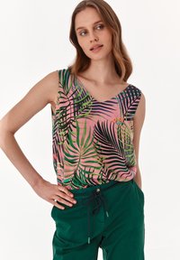 Top di cotone floreale rosa con motivi di foglie di palma verdi e nere. Design a V e tessuto morbido. Abbinato a pantaloni verdi con cordoncino.