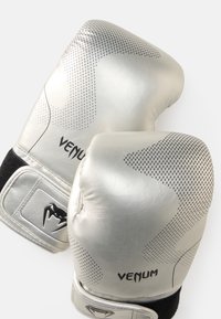 Luvas de boxe prateadas com textura perfurada e detalhes pretos. Apresentam um acabamento em couro liso e uma marcação proeminente da VENUM na superfície.