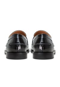 Schwarze Lederlofer mit glatter Oberfläche, nahtlosem Design, runder Zehenpartie und niedriger Gummisohle mit subtilen Nahtdetails entlang der Kanten.