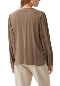 Braune Bluse mit langen Ärmeln, geradem Schnitt, Schulterfalten und klassischem Kragen. Glattes Material mit geknöpften Manschetten.