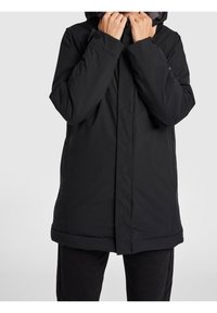 Svart vadderad jacka med huva, med framzip, rak snitt och slät yta, bärs med svarta byxor.