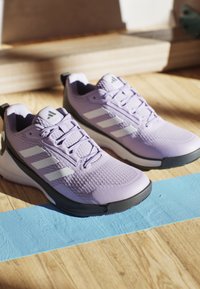 Purple athletic shoes with a textured upper, white stripes, and black accents. Features a sturdy sole and laces for secure fit.