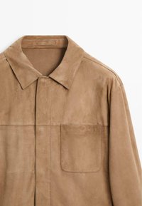 Hellbraune Wildlederjacke mit spitzem Kragen, verdecktem Verschluss vorne und einer einzelnen Tasche auf der linken Brustseite.