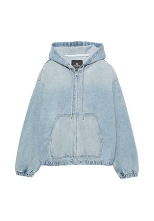 Vaatteena on vaaleansininen denim-parkatakki, jossa on edessä vetoketju, suuri kengurutasku, joustavat hihansuut ja rento malli. Pehmeä, teksturoitu kangas.