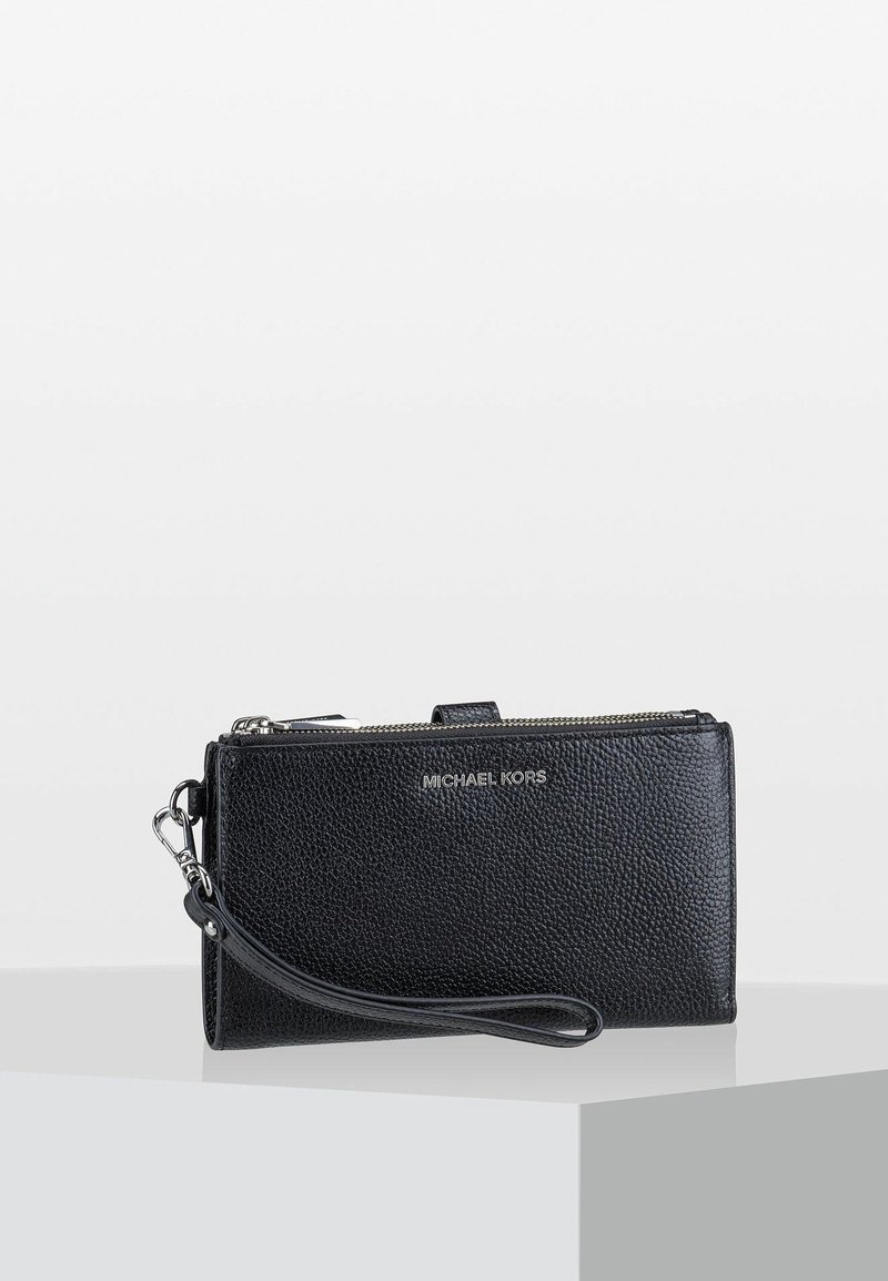 Zwarte leren portemonnee met een gestructureerde afwerking, ritssluiting en polsbandje. Voorzien van de merknaam "Michael Kors" in zilverkleurige letters.