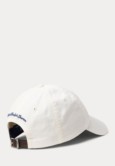 Casquette de baseball en coton blanc avec visière incurvée, sangle en cuir réglable et texte brodé "Polo Ralph Lauren" en bleu marine au-dessus de la sangle.