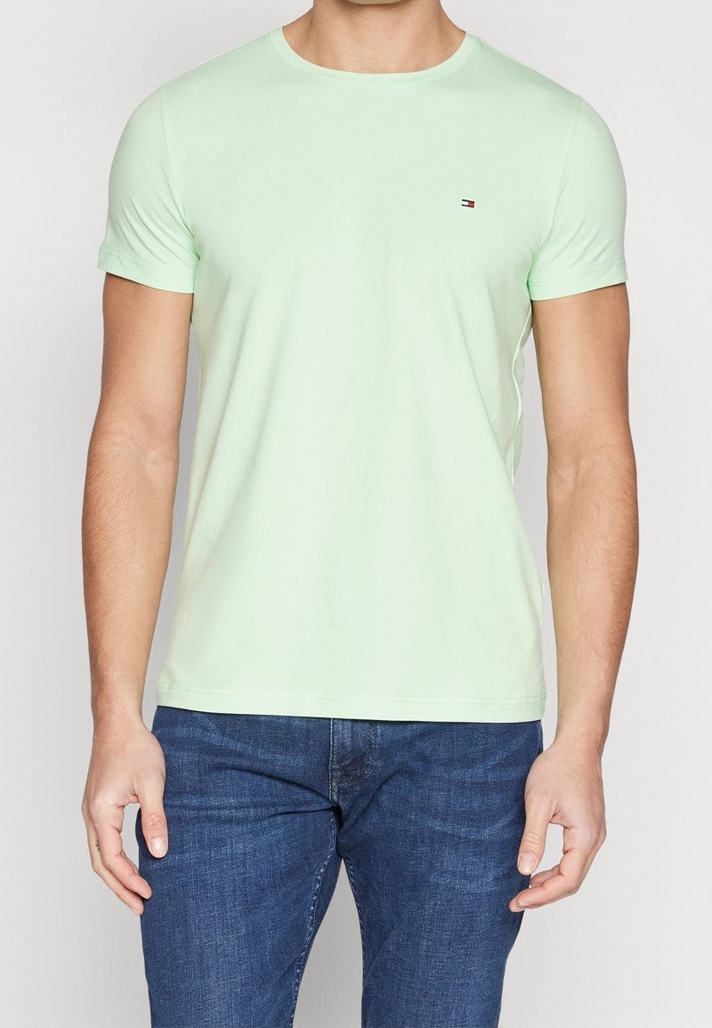 T-shirt vert clair à manches courtes en matière douce, avec un col rond et un petit logo sur la poitrine.