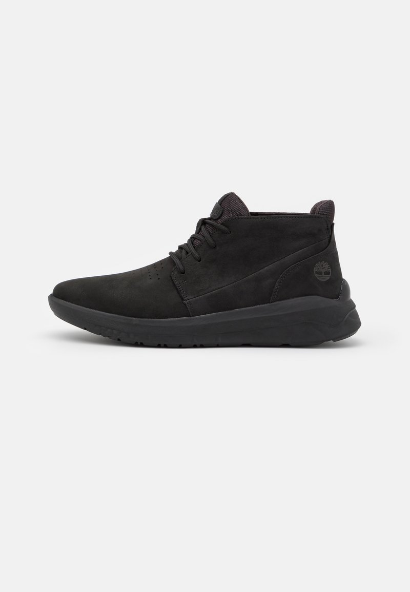 Basket montante noire avec lacets, col rembourré à la cheville, détails cousus et logo arbre Timberland sur le contrefort du talon, vue de côté sur fond uni.
