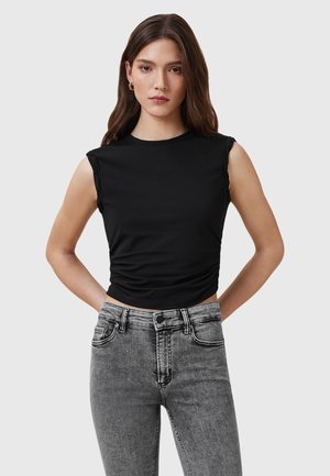 Top nero senza maniche con texture arricciata in vita, abbinato a jeans grigi a vita alta con un classico design a cinque tasche.