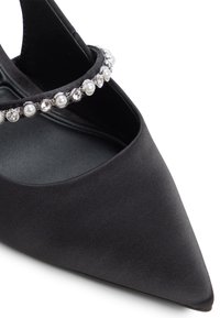 Pump nera in satin con punta affusolata e superficie texturizzata, caratterizzata da un cinturino alla caviglia adornato di strass e perle per un tocco di dettagli.