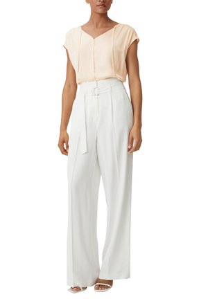 Blusa di satin rosa con maniche corte e scollatura a V; pantaloni bianchi a gamba larga con vita con cintura e texture morbida; sandali con cinturino trasparente.