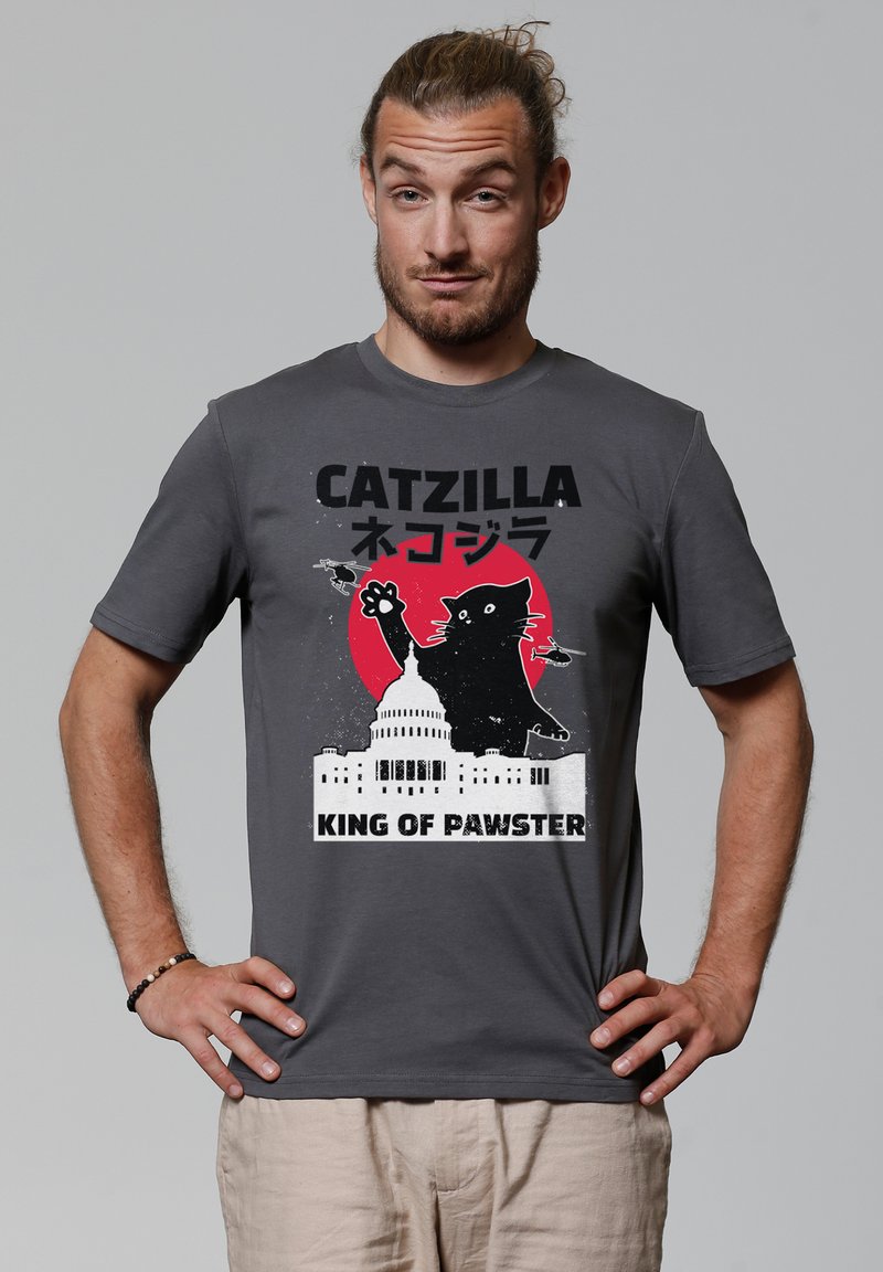 Graues Baumwoll-T-Shirt mit einem grafischen Design, das eine schwarze Katze, einen roten Kreis, das Kapitol und den Text "CATZILLA KÖNIG DER PAWSTER" zeigt. Kurze Ärmel.