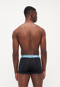 Boxeri negri din materiale elastice cu un tiv al taliei de culoare albastră deschisă cu logo-ul Nike. Designul neted și ajustat îmbunătățește confortul și suportul.