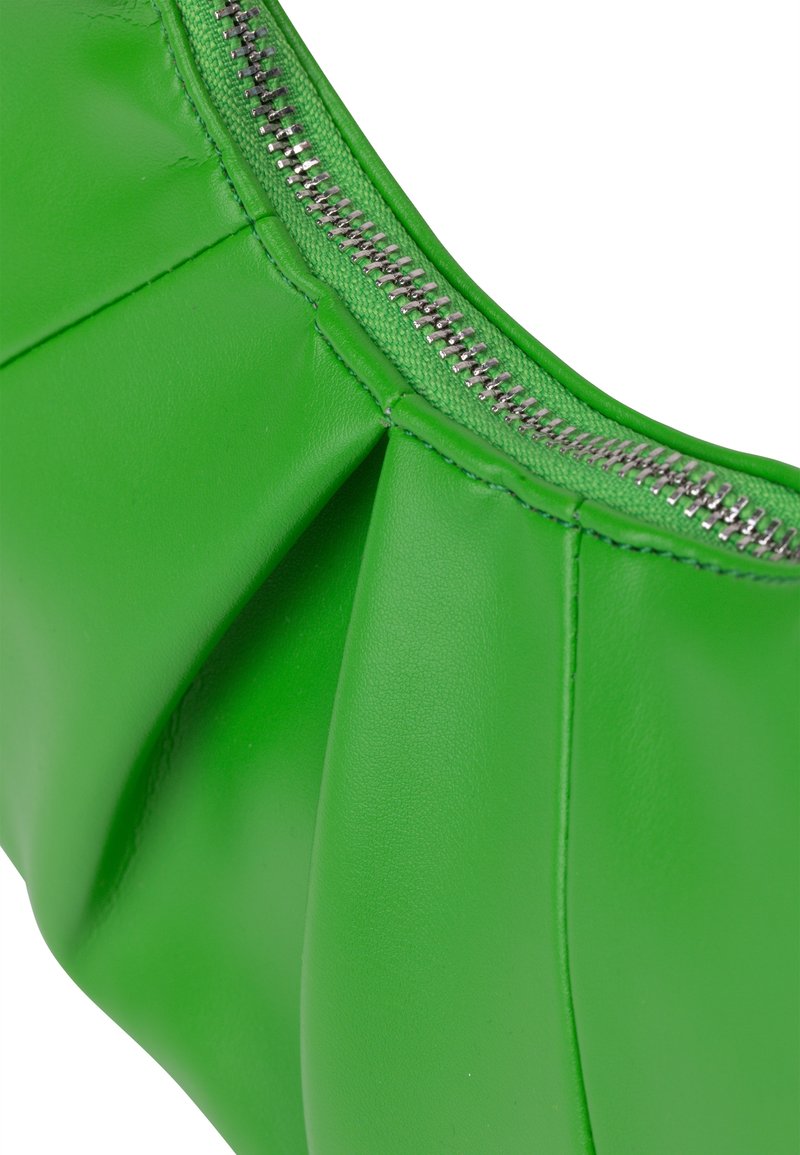 Nahaufnahme eines leuchtend grünen, gefalteten Lederbeutels mit einem sichtbaren silbernen Reißverschluss entlang der oberen Kante.