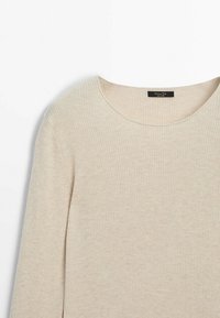 Beige geribd shirt met lange mouwen en ronde hals. Zachte textuur en minimalistisch ontwerp met een zichtbaar label in de halslijn.