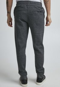 Gray sweatpants with a drawstring waist, tapered legs, and a rear pocket, made from a soft, textured fabric.