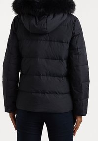 Černá péřová bunda s kapucí, zdobená umělou kožešinou. Horizontálně prošívaná textura, střední délka a přiléhavý střih.