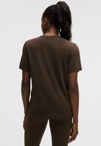 Braunes T-Shirt mit kurzen Ärmeln und Rundhalsausschnitt, hergestellt aus einem glatten Stoff. Es hat eine lockere Passform und einen geraden Saum.