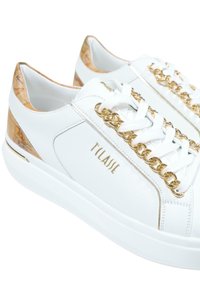 Sneakers bianchi in pelle con un accento di catena dorata sui lacci e un pannello posteriore texturizzato color noce con un motivo sottile.