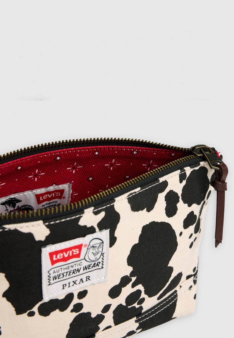 Lille lynlås-pung med sort og hvid kvægprint, rød mønstret indvendig og Levi's Pixar Western Wear etiket.