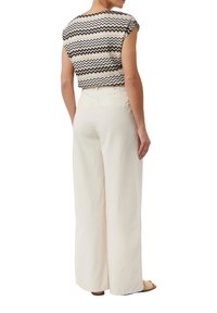 Zwart-wit zigzag patroon top gecombineerd met losse, crème-kleurige linnen broek, met een hoge taille en wijde pijpen.