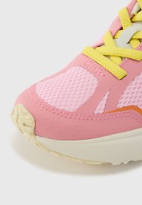 Ροζ αθλητικό παπούτσι με πλέγμα πάνελ, κίτρινα κορδόνια και πορτοκαλί λεπτομέρειες. Στρογγυλερή μύτη, μαλακή σόλα και υφή στην επάνω επιφάνεια.