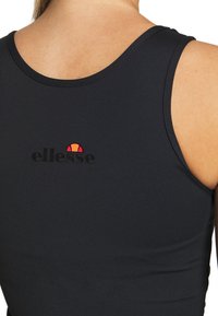 Svart atletisk linne med rund halsringning, med en liten flerfärgad logotyp på ryggen och en figurnära design. Slät textur.