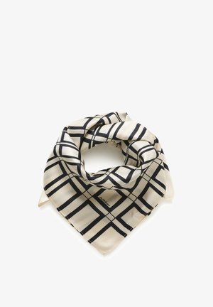 Kvinde iført en sort sweater, sorte læder knælange shorts, sorte læder knæstøvler og et beige mønstret halstørklæde.