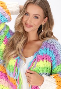 Dažādkrāsains blīvs adījuma kardigāns ar spilgtām svītrām purpursarkanā, rozā, oranžā, zaļā un zilā krāsā. Plata, strukturēta piedurkne un viegla adījuma materiāls.