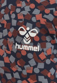 Mönstrad tyg t-shirt med geometriska former i röd, grå och marinblå, med en vit "hummel"-logotyp på framsidan. Strukturerad yta.