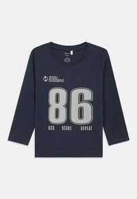 Námořnická modrá dětská košile s dlouhým rukávem, na přední straně s velkými číslicemi "86", malým fotbalovým míčem a textem "Goal Diggers" a "Kick Score Repeat".
