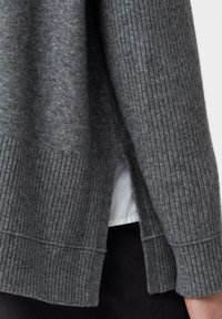 Grauer gestrickter Pullover mit gerippten Bündchen und Saum, der seitliche Schlitze für optimale Bewegungsfreiheit aufweist. Weiche Textur, lässiges Design.