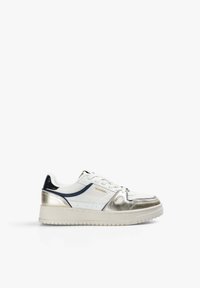 Zapatilla baja blanca y dorada metálica con detalles en navy, diseño con cordones y suela texturizada beige, mostrada en perfil lateral derecho.