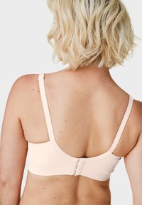 Różowy stanik z elastycznego materiału, z regulowanymi ramiączkami, gładkim tyłem oraz zapięciem na haczyk dla zapewnienia stabilnego dopasowania. Minimalistyczny design.