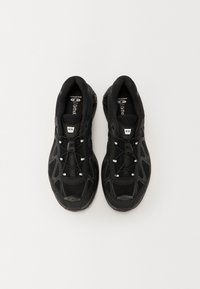 Fekete sportcipő lélegző hálós felsőrésszel, fényvisszaverő részletekkel, párnázott talppal és fűzőrendszerrel. A kényelem és a teljesítmény érdekében tervezve.