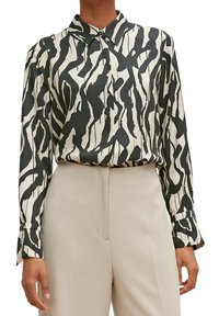 Silk long-sleeve blouse with a black and white abstract pattern, button-down collar, and fitted cuffs, paired with beige tailored pants.