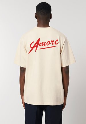 T-shirt en coton beige avec une inscription rouge "Amore" dans le dos. Manches courtes, coupe décontractée, avec un col rond.