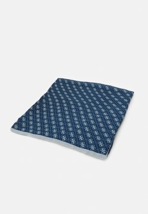 Carré de tissu bleu avec motif monogramme blanc répété, posé à plat sur un fond clair uni.