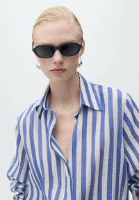 Schwarze ovale Sonnenbrille, blau-weiß gestreiftes Hemd, weicher Stoff, lockere Passform, auffälliger offener Kragen, glatte Textur, minimalistisches Design.
