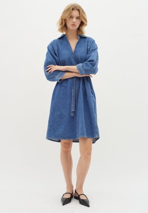 Jeansjurk met een kraag, driekwart mouwen en een cinched taille. Kenmerkt zich door een knie-lange snit en contrasterende stiksels.