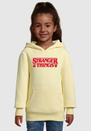Gul hættebluse med en forlommer og rød "STRANGER THINGS" grafik. Har ribbede manchetter og kant, blød materiale tekstur.