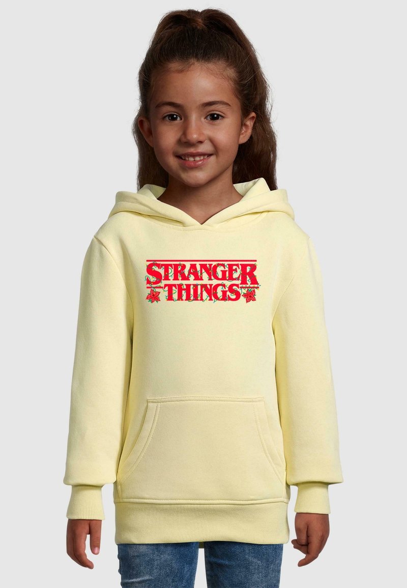 Gul luvtröja med ficka fram och röd "STRANGER THINGS" grafik. Har ribbade muddar och nederkant, mjukt material.