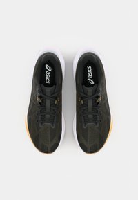 Baskets de sport vert foncé avec une texture lisse, présentant un motif en diamant, des lacets noirs, des semelles blanches et des accents orange sur la semelle extérieure.