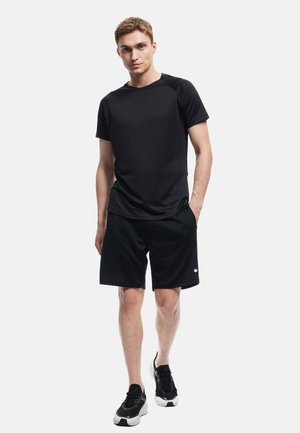Czarny sportowy T-shirt z okrągłym dekoltem, w połączeniu z czarnymi szortami. Oba elementy wykonane są z gładkiego, lekkiego materiału. Czarne sneakersy dopełniają wygląd.