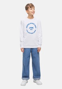 Vit crewneck sweatshirt med blå grafisk text, tillsammans med ljusblå vida jeans och vita sneakers; avslappnad passform och mjuk textur.