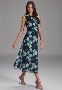 Blumen-Maxikleid in Dunkelblau mit grünen und weißen Blumenmustern. Ärmelloses Design, taillierter Oberteil, fließender Rock, leichtes Material.